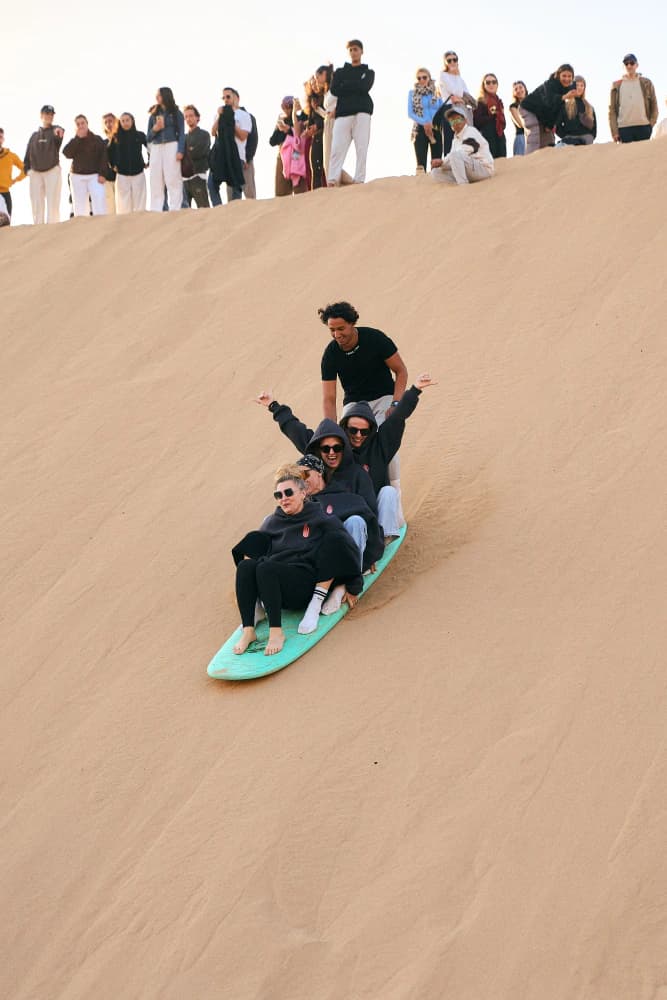 Group sandboarding desert dune at Aman Surf & Yoga in Imsouane, Morocco