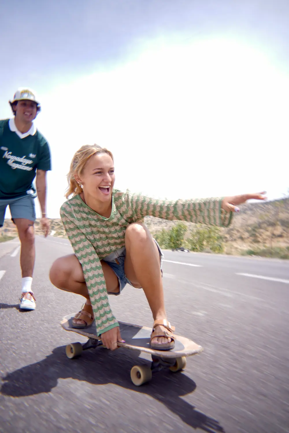 Guided Surfskate Session Smiling guest riding low on a surfskate with a coach behind her in Imsouane, Morocco.